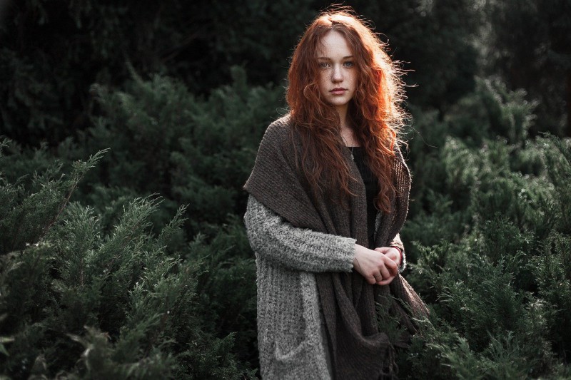 Redheaded girl wearing layers of clothes in nature