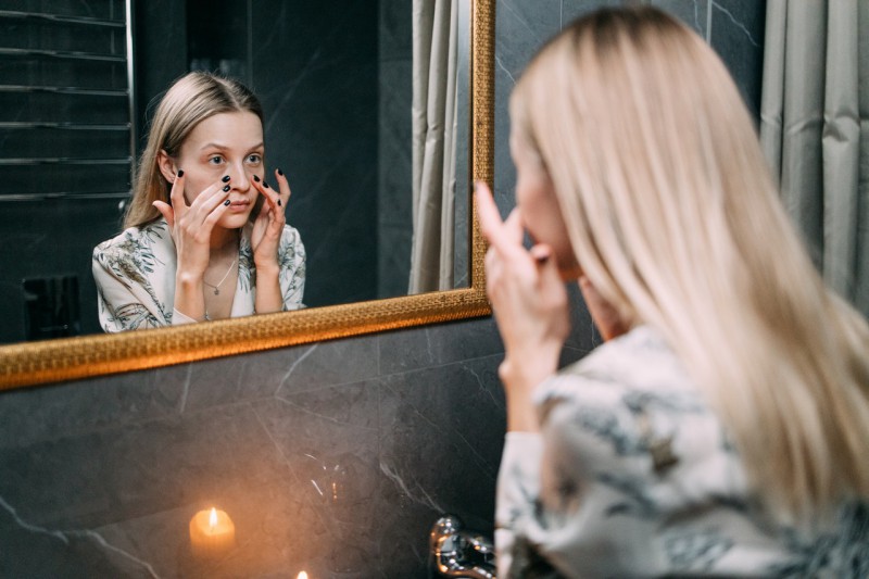 A girl looking at her face in the mirror.