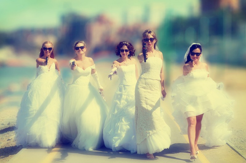 Five women in wedding dresses holding guns