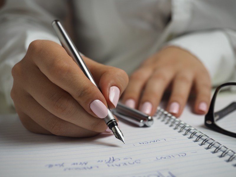 A woman with painted nails writing