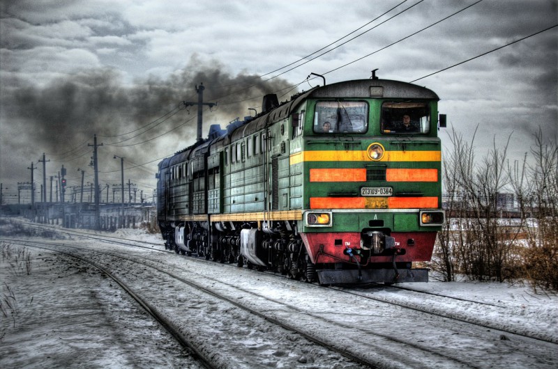 A gas-powered locomotive going over snow-covered track.