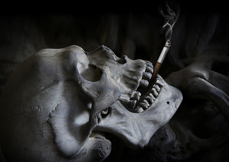 A human skull with a smoking cigarette in mouth