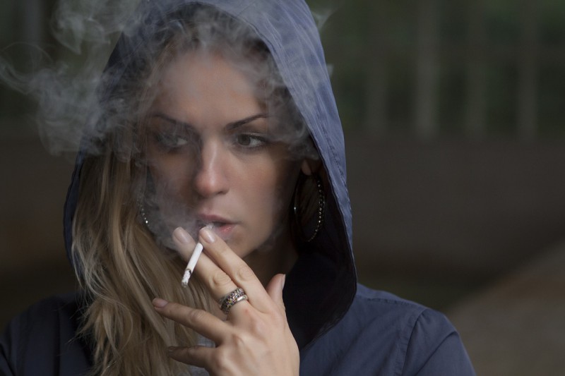 A young woman with a hoodie smoking