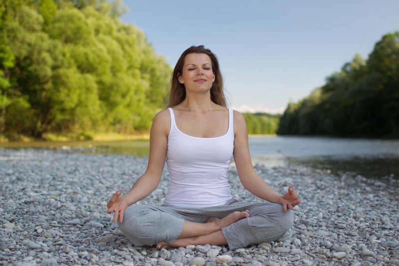 A woman practicing yoga by the water