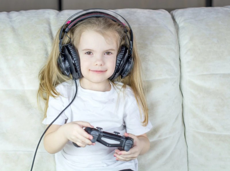 A girl with headphones holding a PS4 gamepad