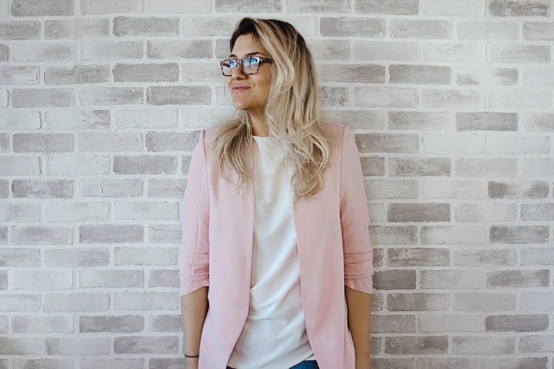 A blonde woman with glasses wearing pink blazer