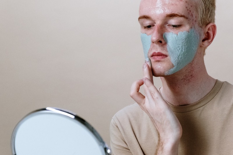 A guy putting on a clay mask
